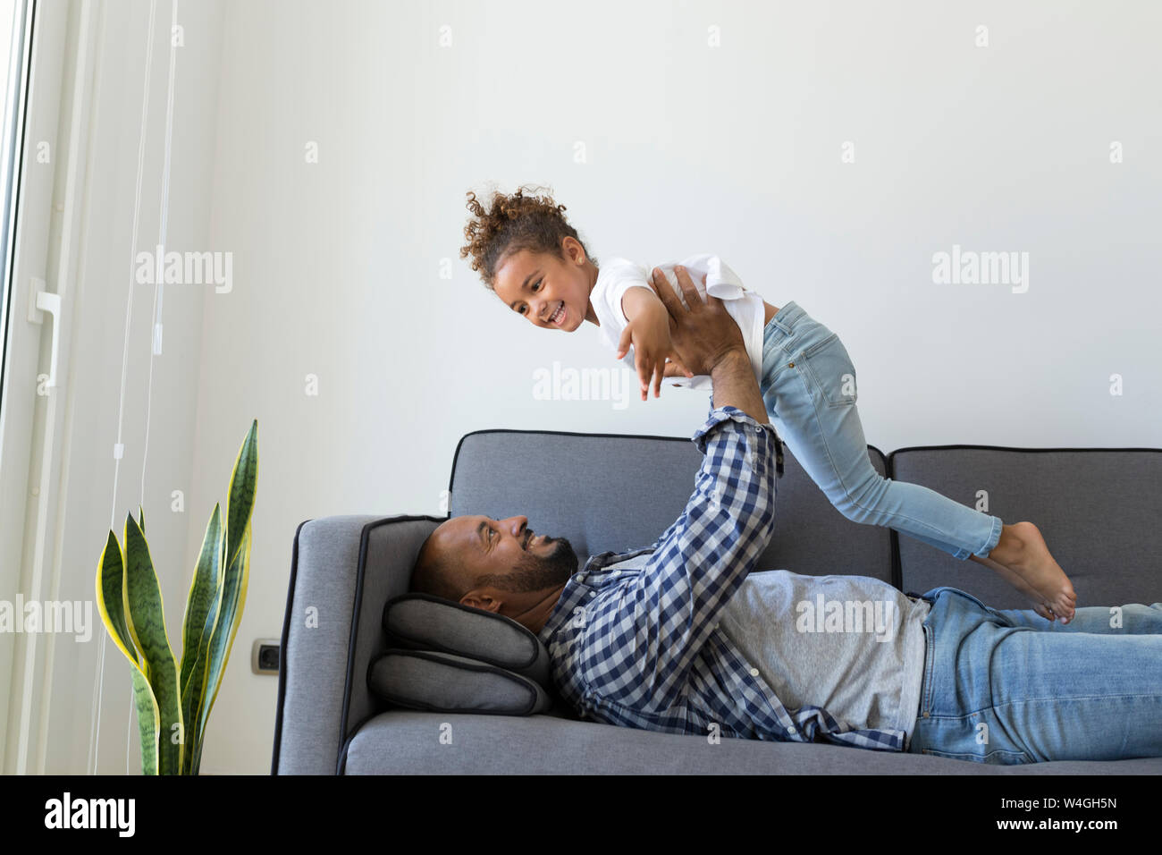 Felice padre e figlia giocando sul lettino a casa Foto Stock