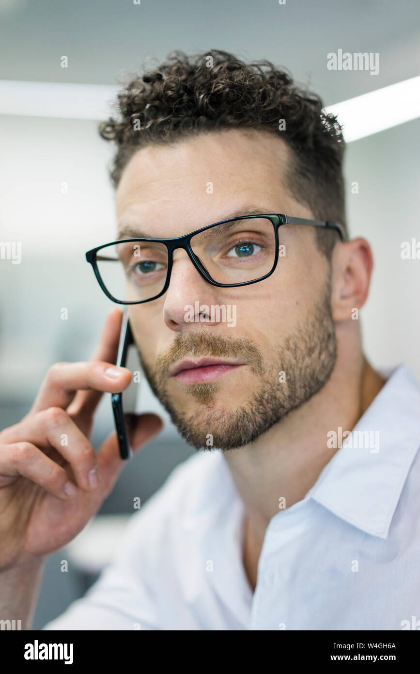Ritratto di imprenditore sul telefono cellulare in ufficio Foto Stock