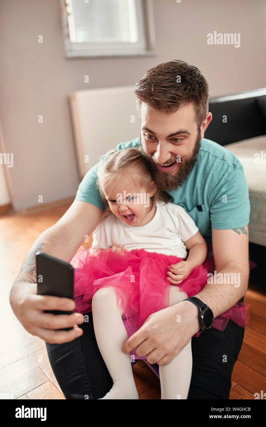 Padre e figlia prendendo un selfie, ragazza indossando rosa tutu Foto Stock