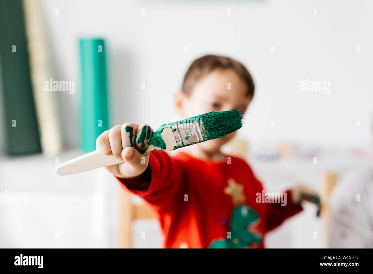 Bambino con una spazzola in mano fare artigianato a casa Foto Stock