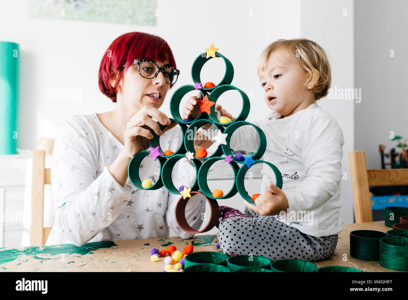 Madre e figlia fare artigianato a casa con accessori per fare un albero di Natale Foto Stock