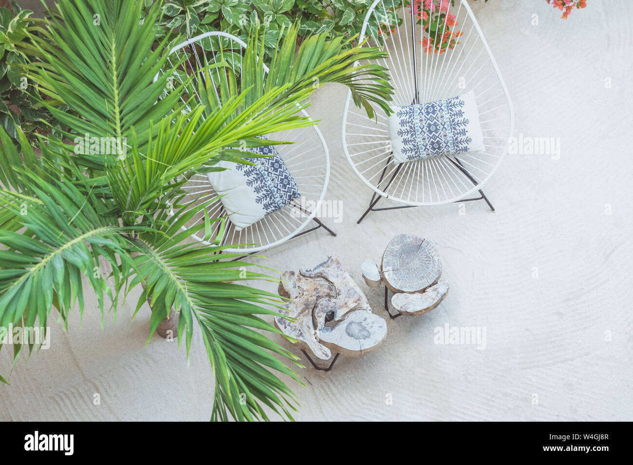 Outdoor sedie e tavoli di legno in piedi oltre ad un albero di palme sulla spiaggia sabbiosa Foto Stock