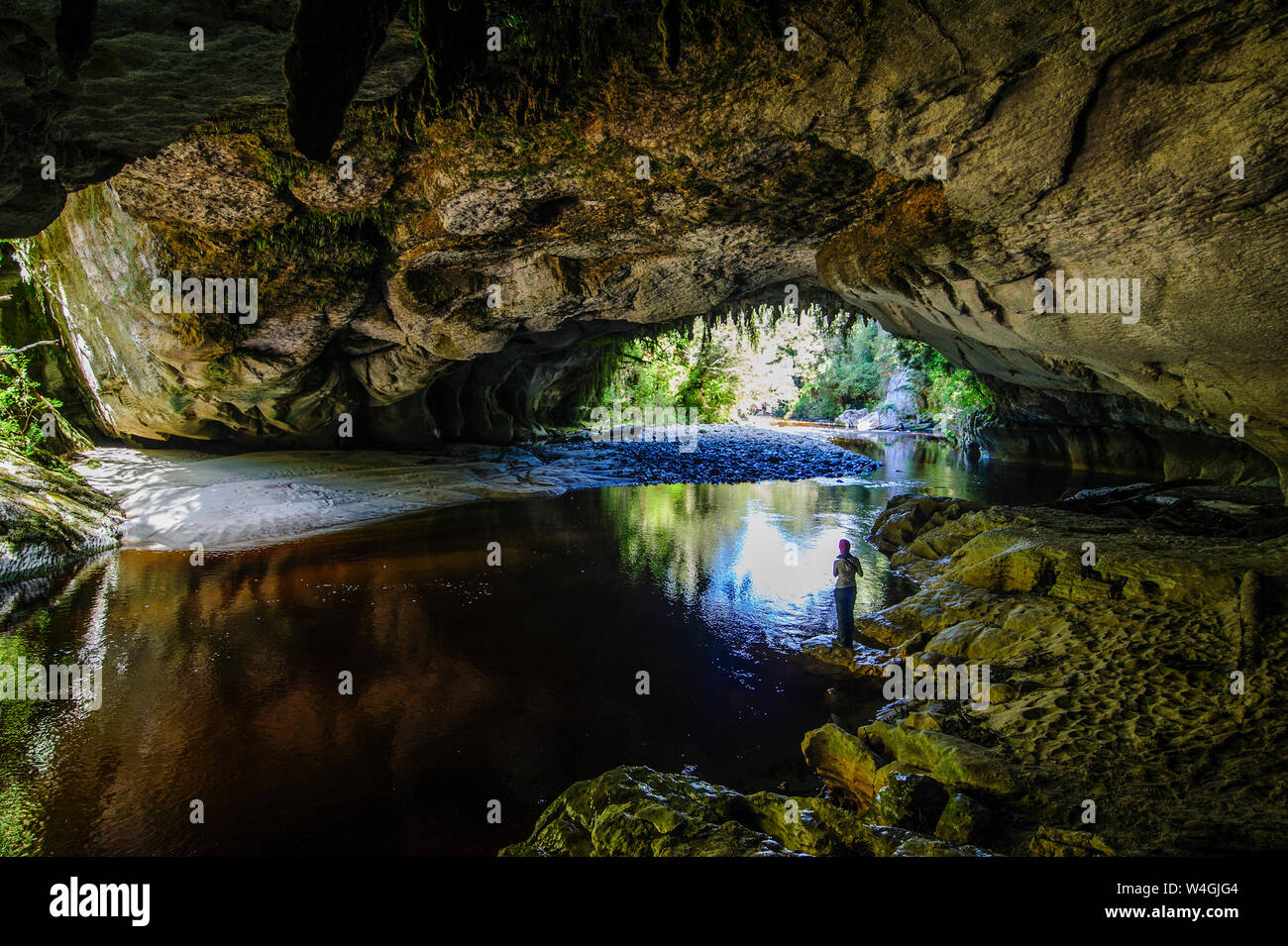 Donna godendo la splendida Porta di Moria Arch nel bacino Oparara, Karamea, Isola del Sud, Nuova Zelanda Foto Stock