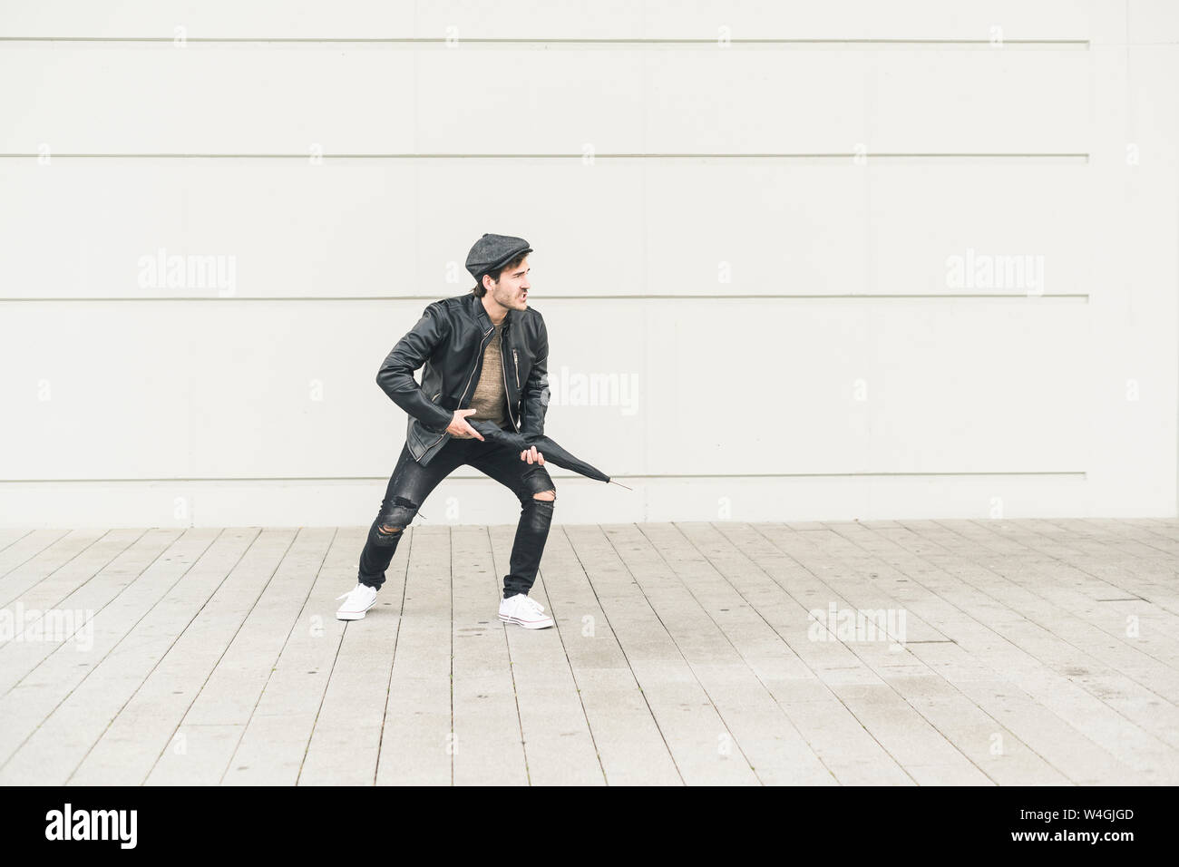 Giovane uomo fingendo di sparare con ombrello chiuso Foto Stock