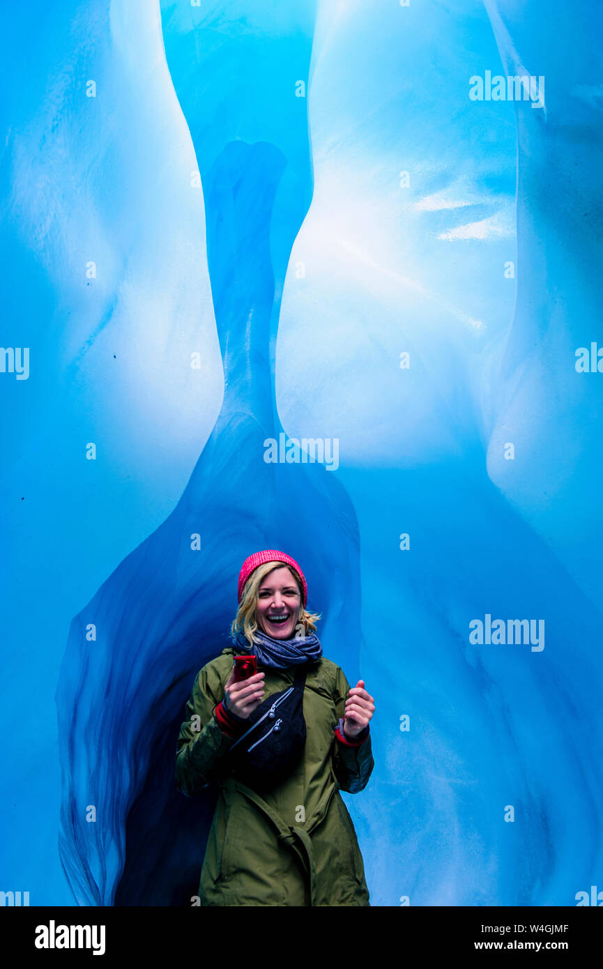 Donna felice in una caverna di ghiaccio, Fox Glacier, Isola del Sud, Nuova Zelanda Foto Stock