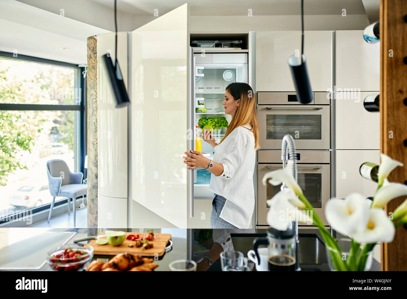La donna in cucina moderna con frigorifero di apertura Foto Stock