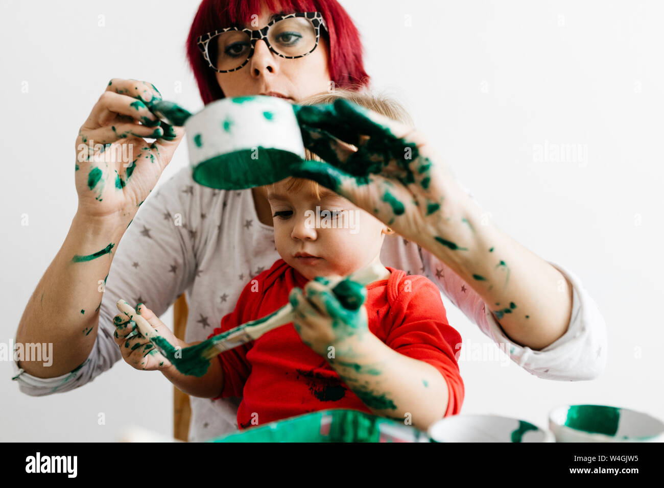 Madre e figlia fare artigianato a casa pittura rotoli di cartone Foto Stock