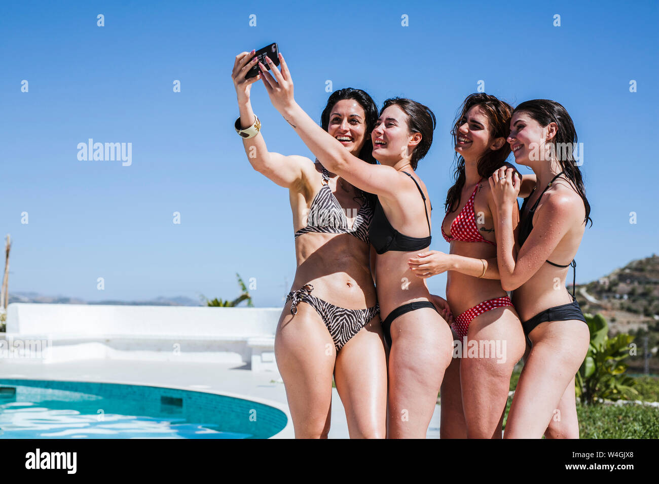 Giovani donne godendo il periodo estivo presso la piscina, prendendo un selfie Foto Stock