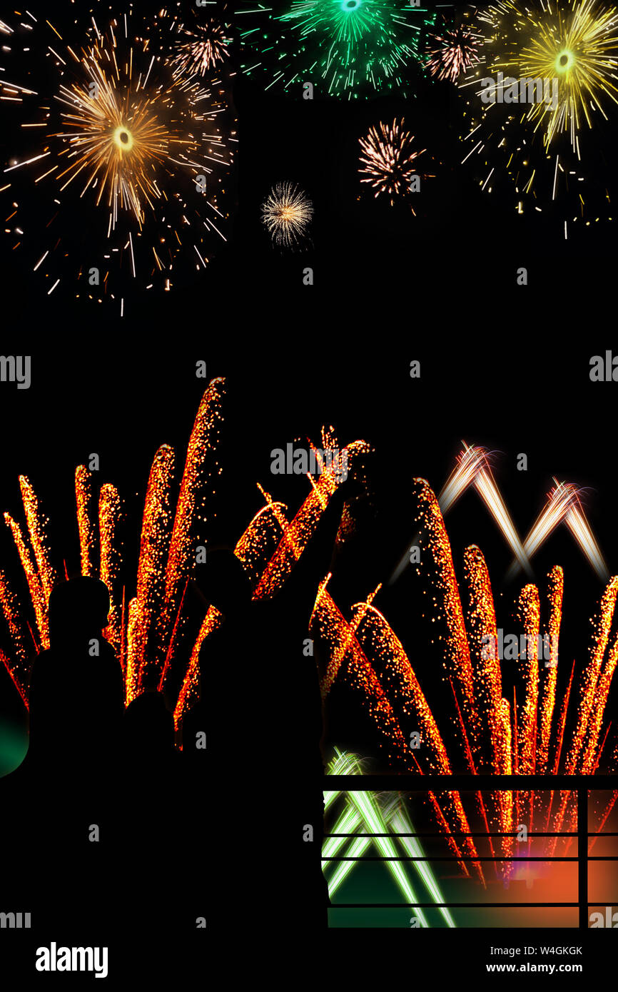 Silhouette di una famiglia che guarda fuochi d'artificio esplodere di notte Foto Stock