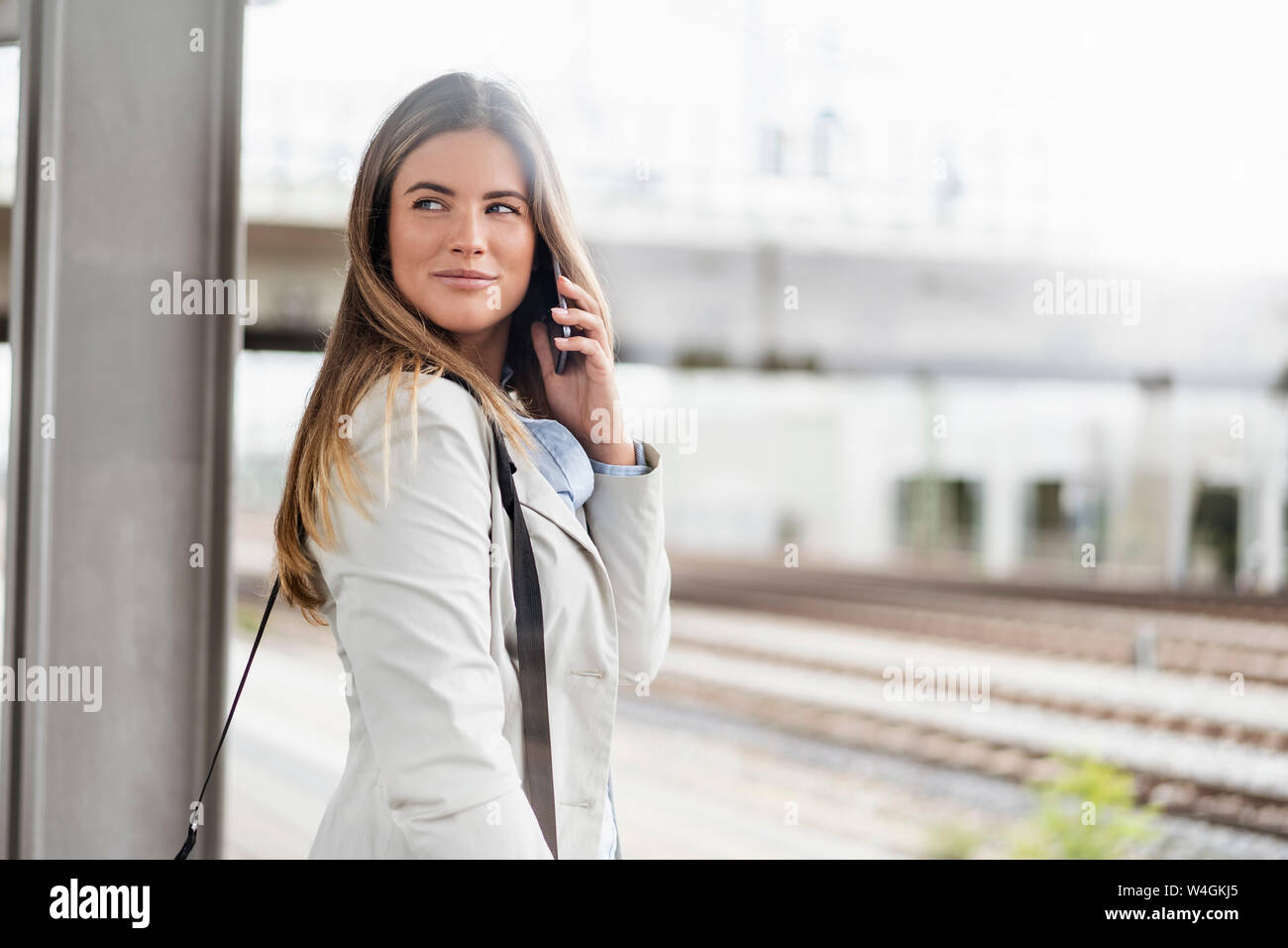 Giovane imprenditrice utilizza lo smartphone, in piedi sulla stazione Foto Stock