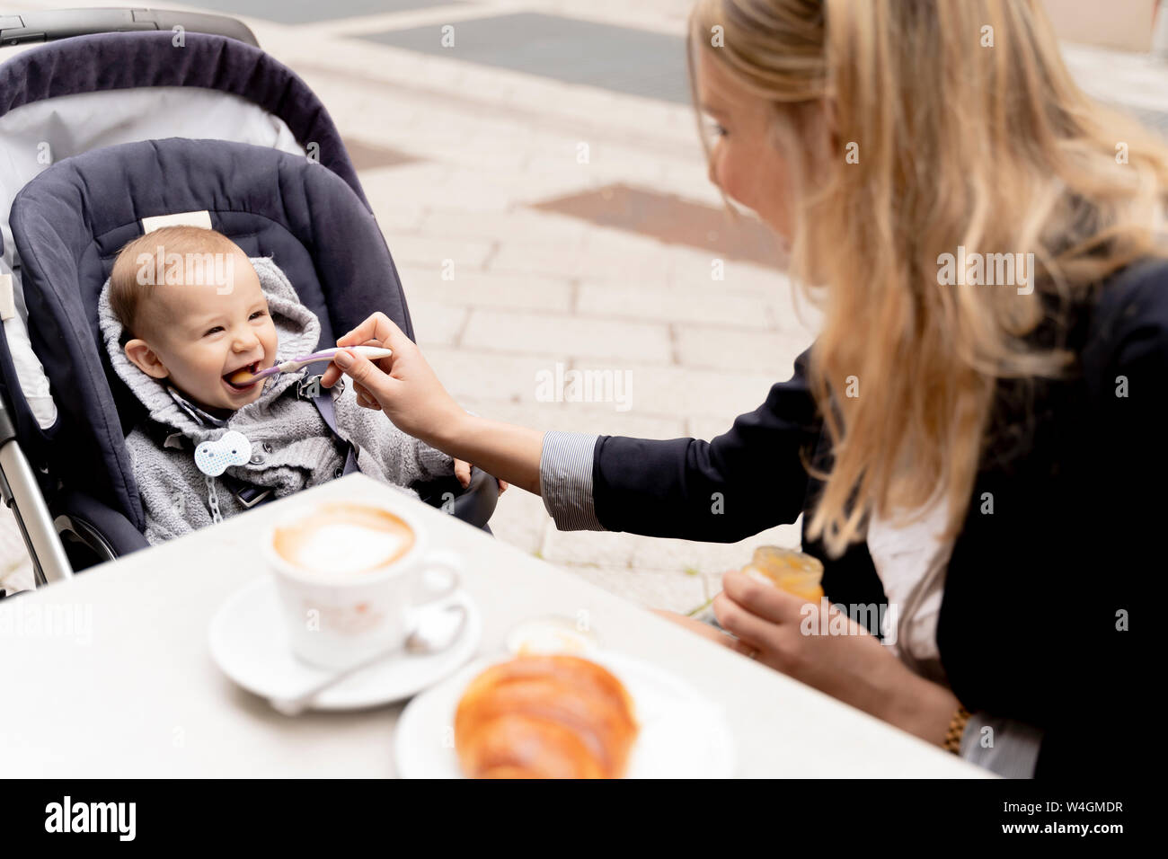 Alimentazione madre Laughing baby boy in passeggino Foto Stock