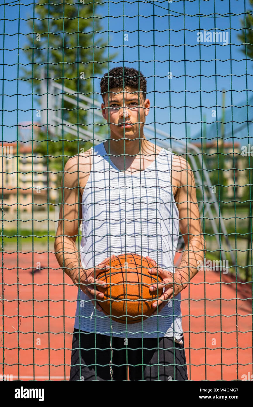 Giovane uomo con basket dietro al netto Foto Stock