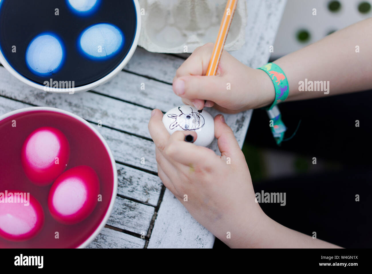 Close-up di ragazza faccia di pittura su uovo di pasqua sul tavolo da giardino Foto Stock