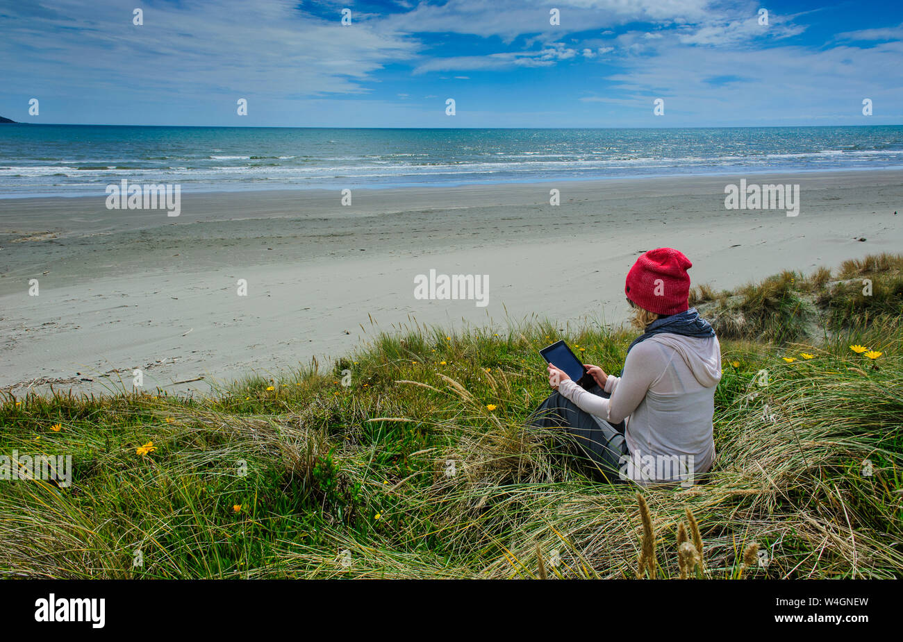 Donna che utilizza tablet a Foxton beach, la Costa di Kapiti, Isola del nord, Nuova Zelanda Foto Stock
