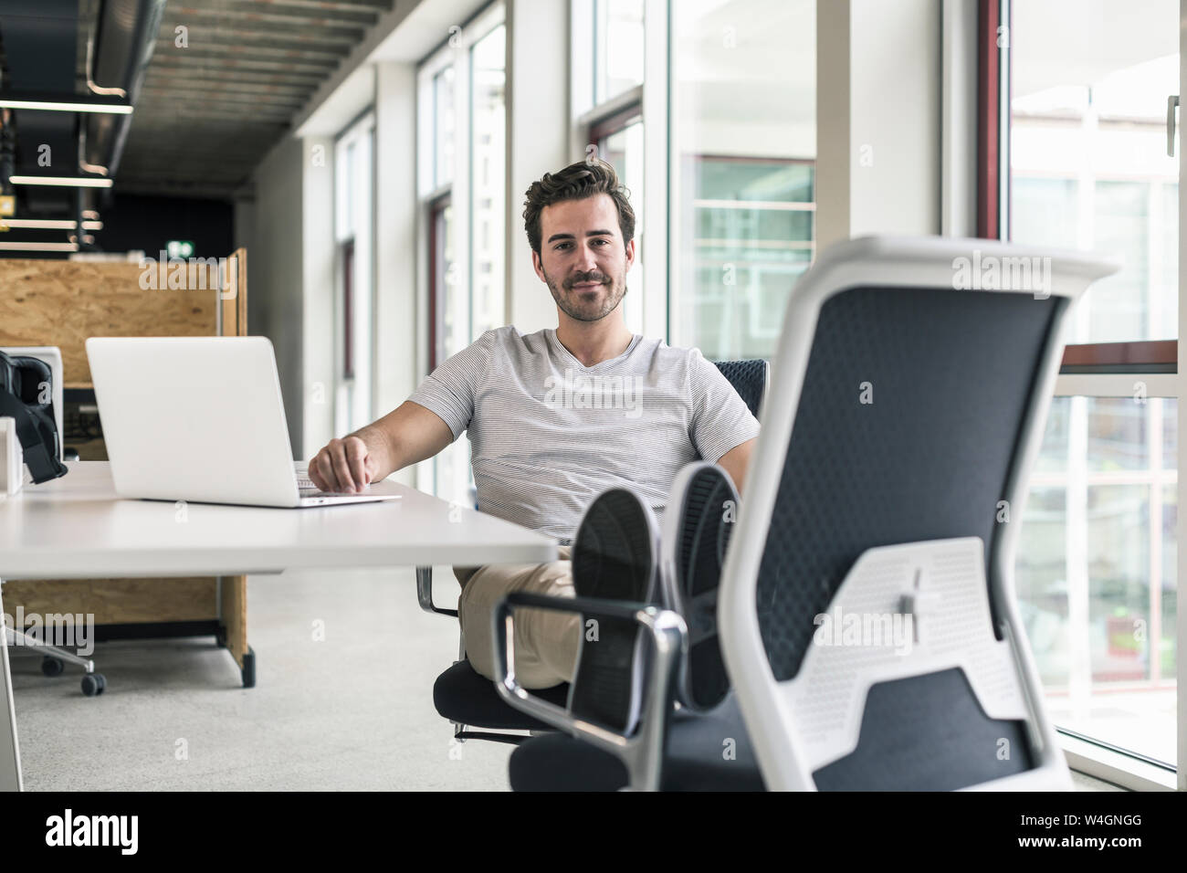 Giovane imprenditore lavora rilassato in un ufficio moderno, pensando Foto Stock
