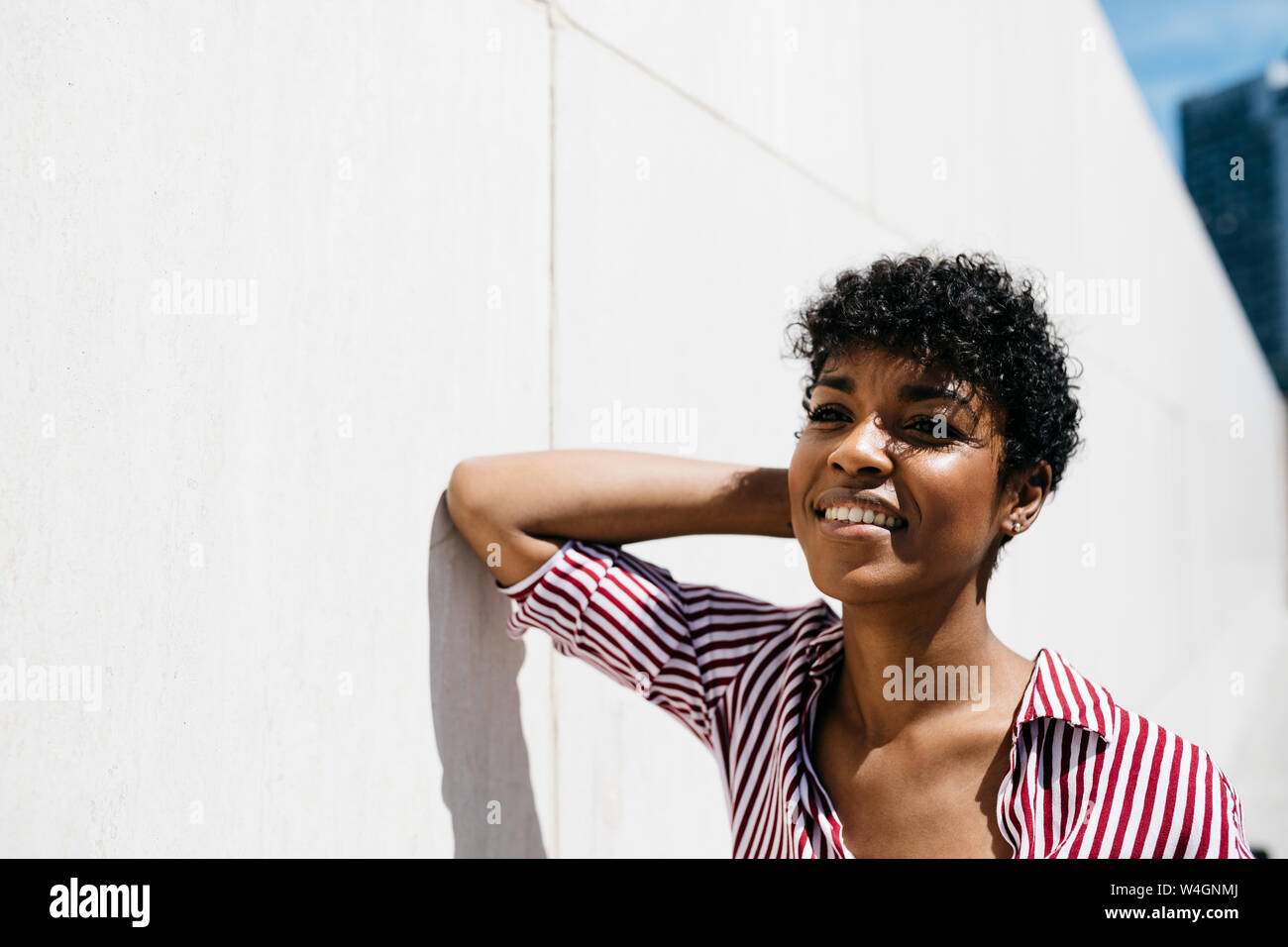 Ritratto di donna sorridente appoggiato su una parete Foto Stock