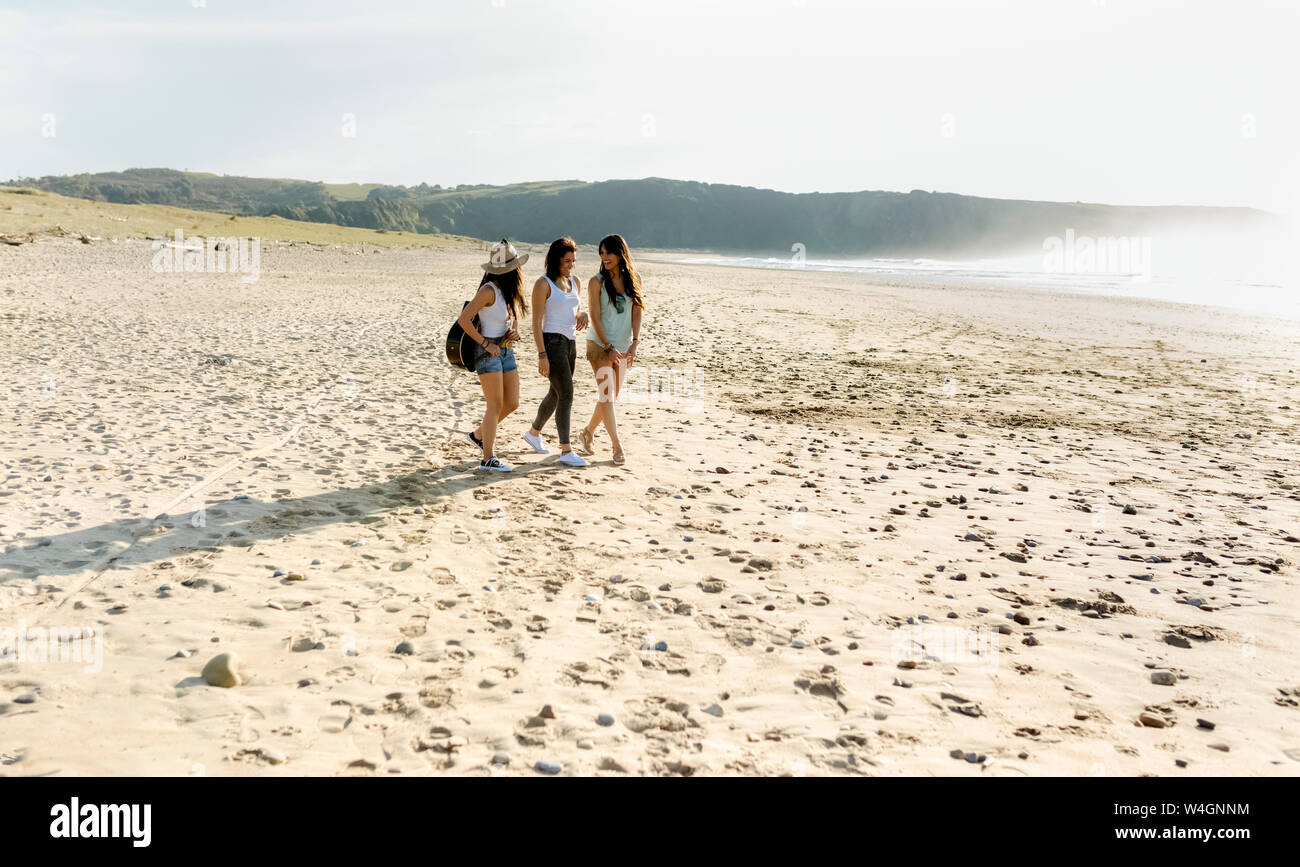 Tre donne con la chitarra di camminare sulla spiaggia Foto Stock