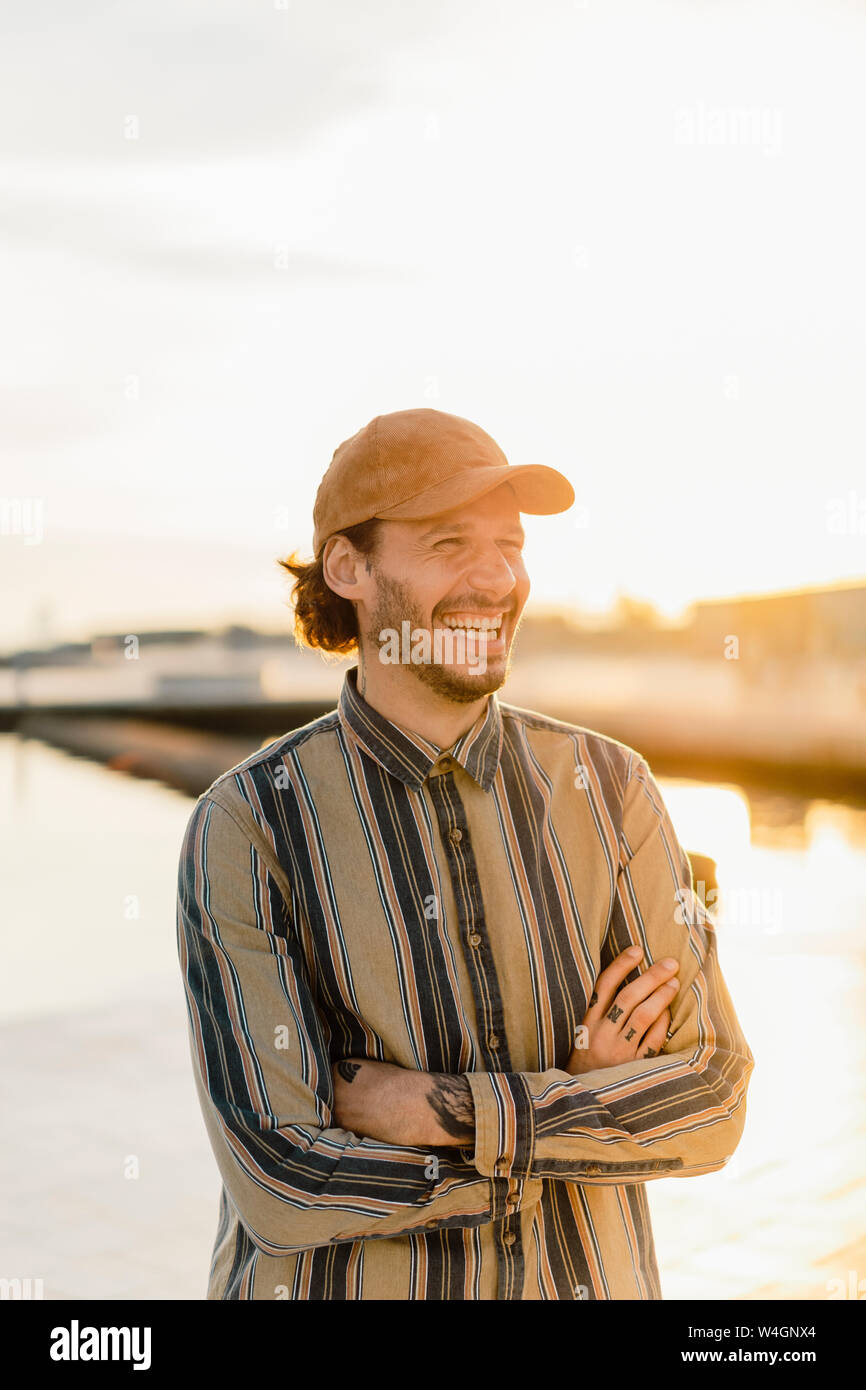 Prtrait di ridere uomo che indossa cappello da baseball e strisce shirt al tramonto Foto Stock