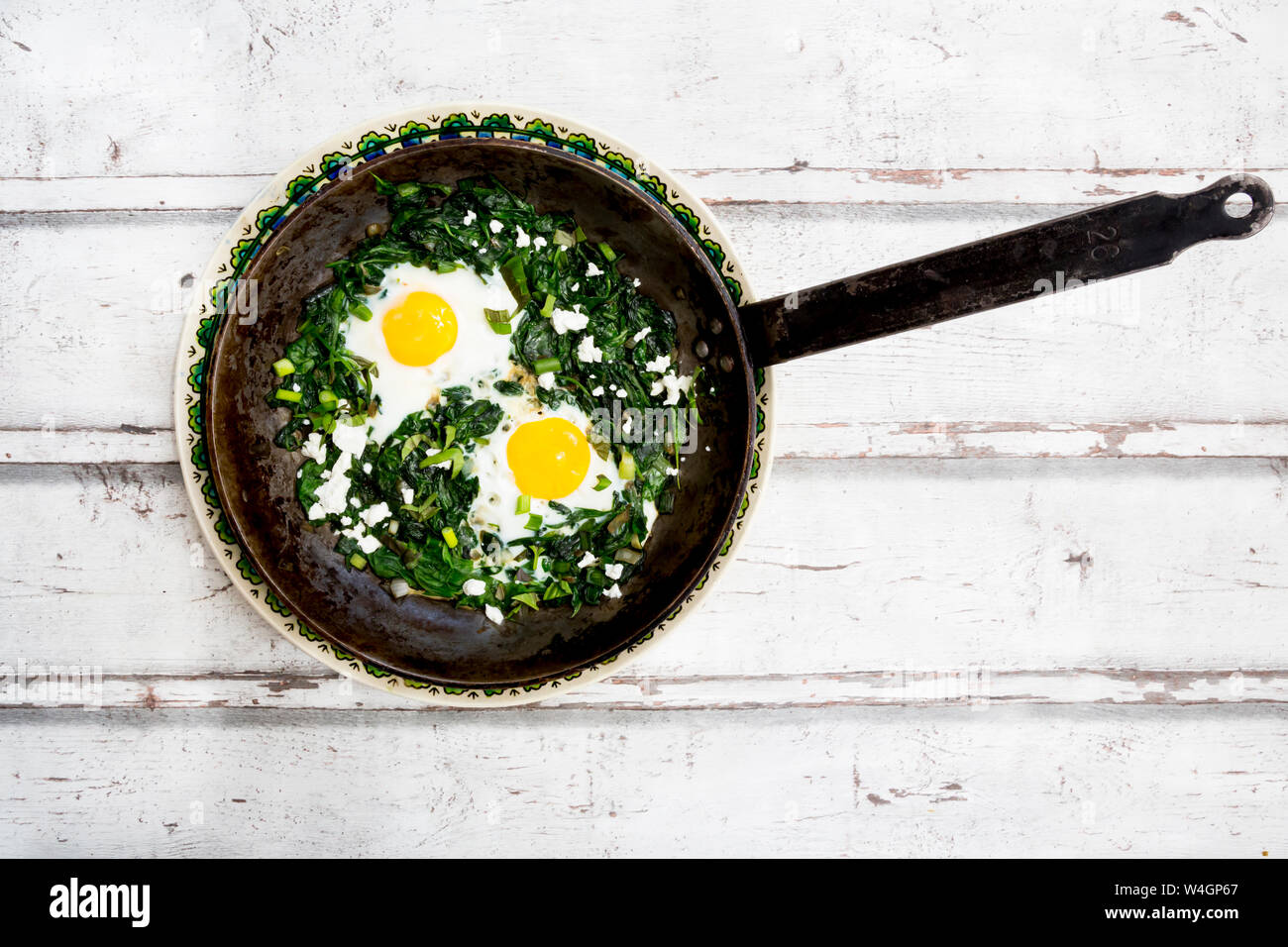 Shakshouka verde con baby spinaci, bietole, cipolline e basilico in una padella Foto Stock