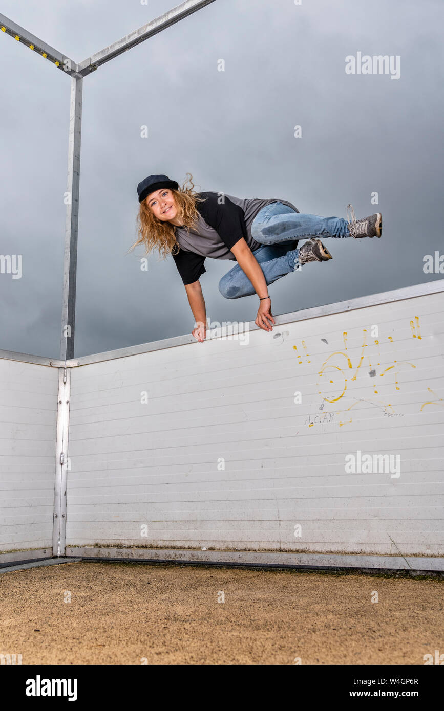 Ritratto di giovane donna saltando su barriera Foto Stock