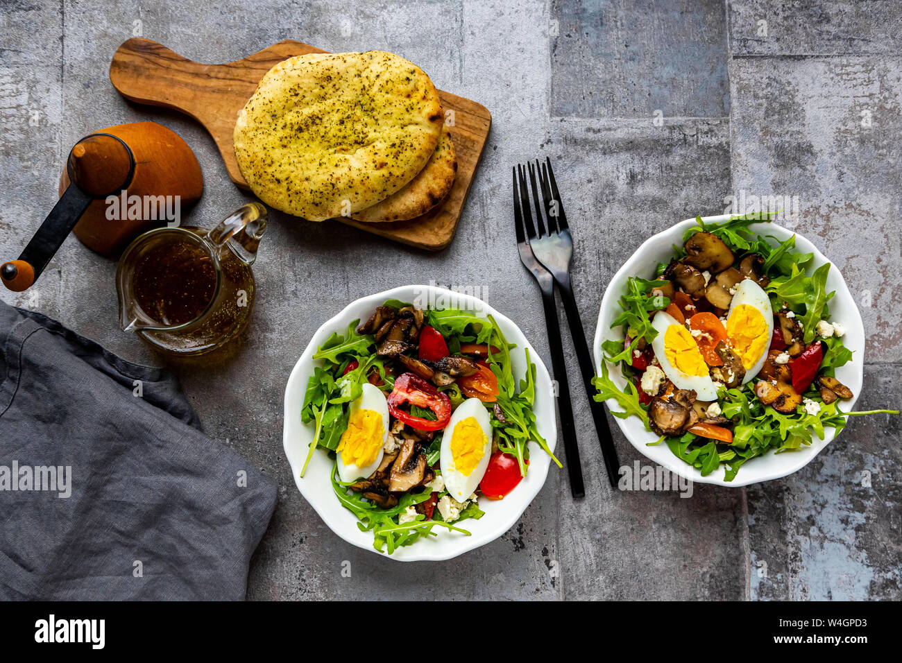 Insalata di rucola con champignon fritti, uova sode, pomodori e formaggio feta Foto Stock