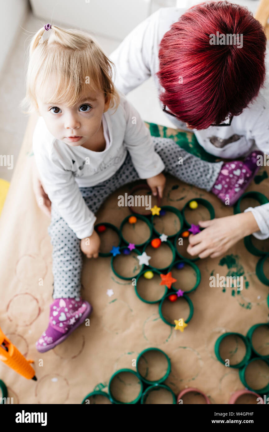 Vista superiore della madre e figlia fare artigianato a casa con accessori per fare un albero di Natale Foto Stock