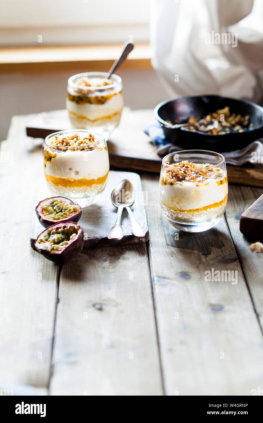 Cheesecake crudi in un bicchiere con il frutto della passione e il dado fragile Foto Stock