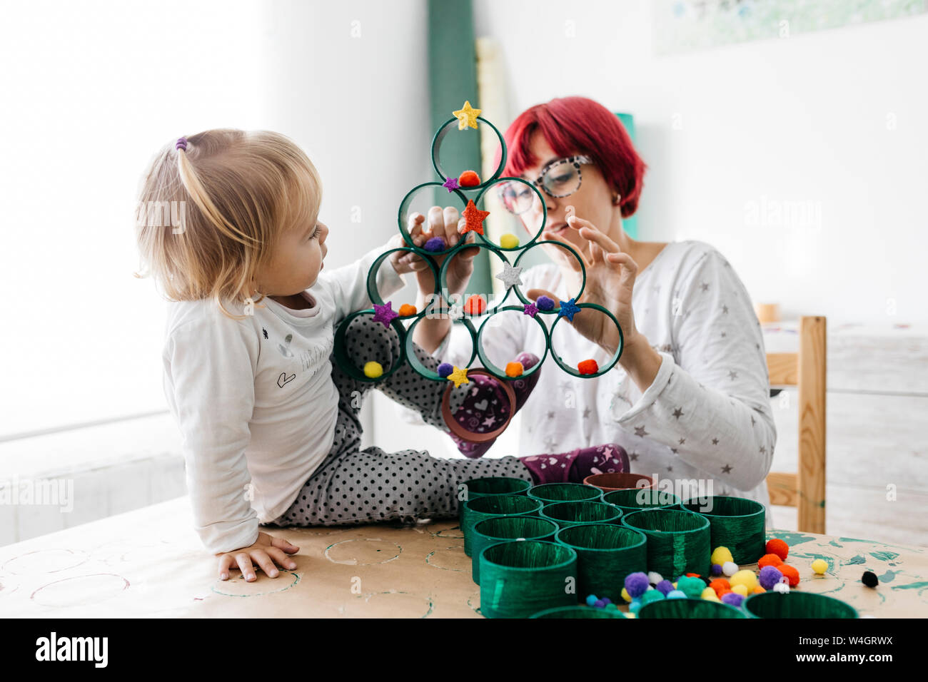 Madre e figlia fare artigianato a casa con accessori per fare un albero di Natale Foto Stock