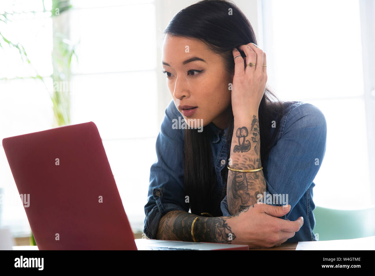 Donna che utilizza il portatile in tabella in ufficio Foto Stock