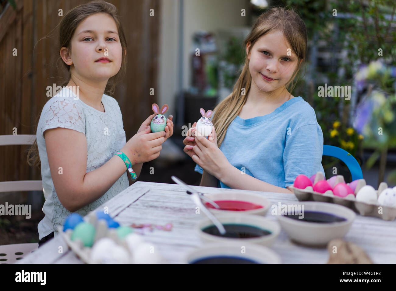 Ritratto di due ragazze decorare le uova di Pasqua sul tavolo da giardino Foto Stock