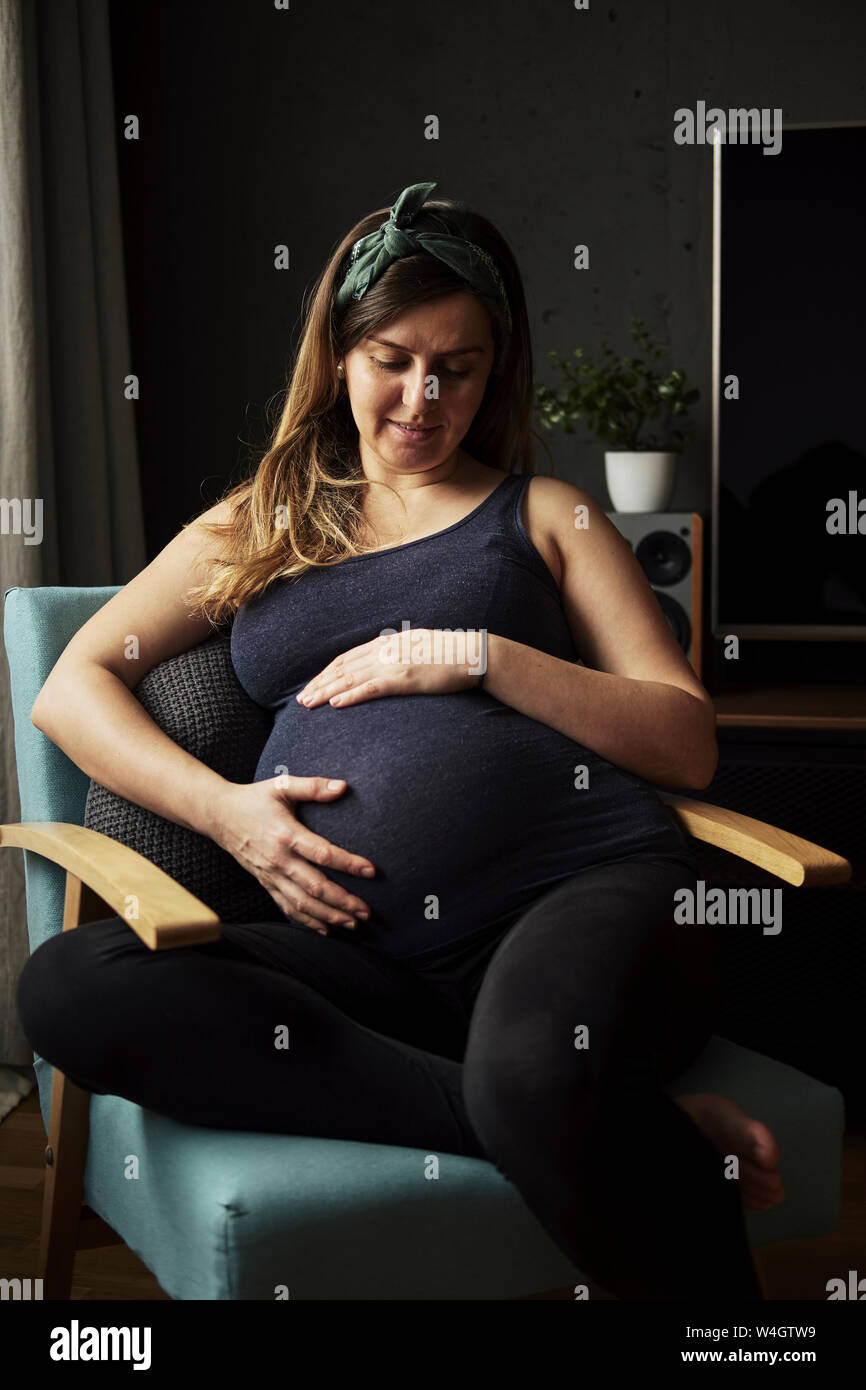 Donna incinta guardando sul suo ventre bambino a casa Foto Stock