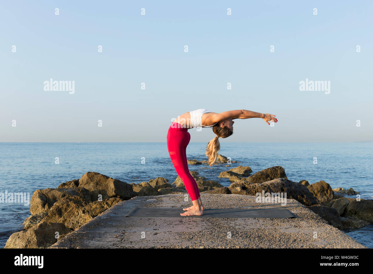 Giovane donna a praticare yoga sulla spiaggia, fare uno sfondo Foto Stock