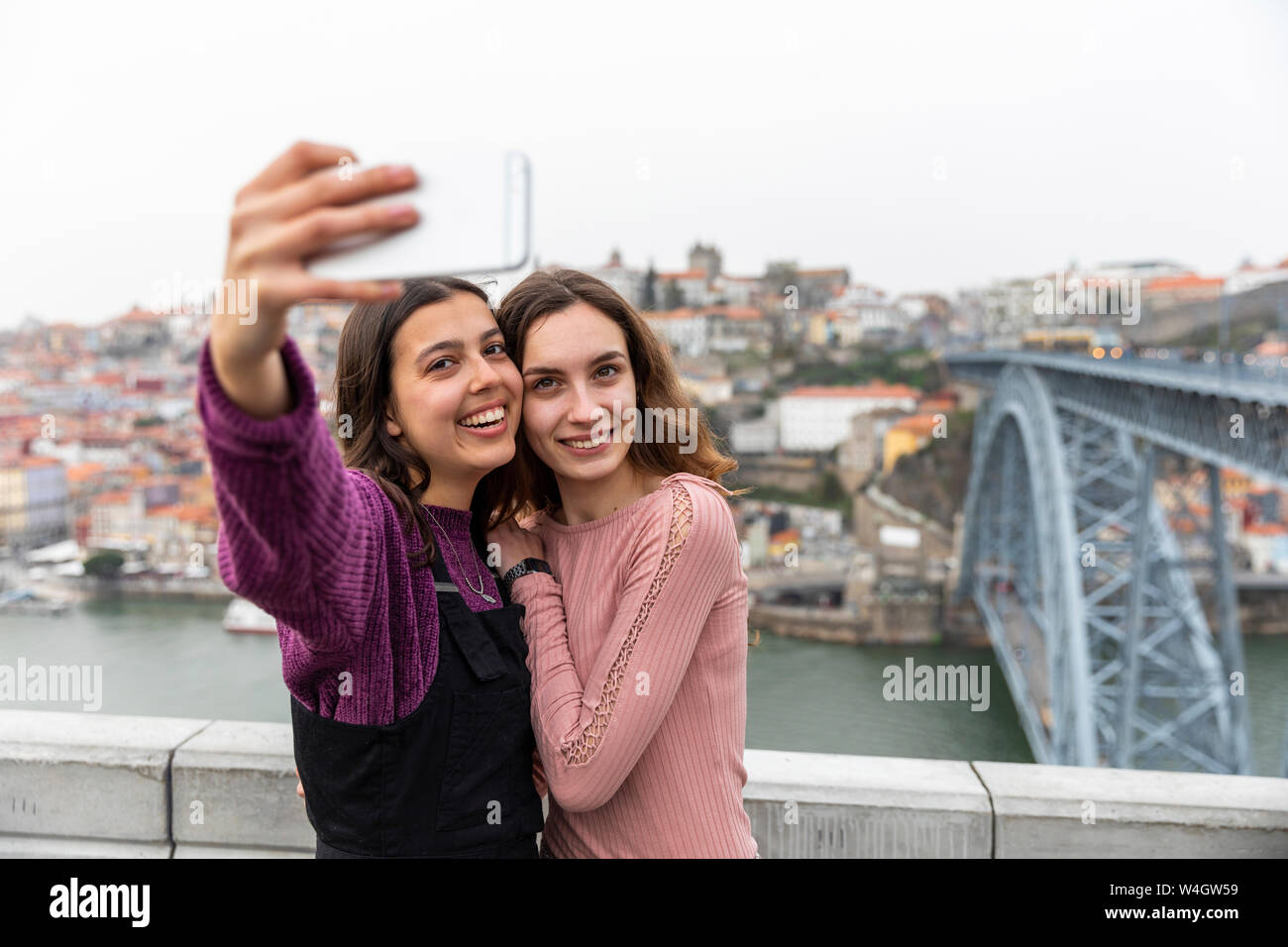 Ritratto di due migliori amici prendendo selfie con lo smartphone, Porto, Portogallo Foto Stock