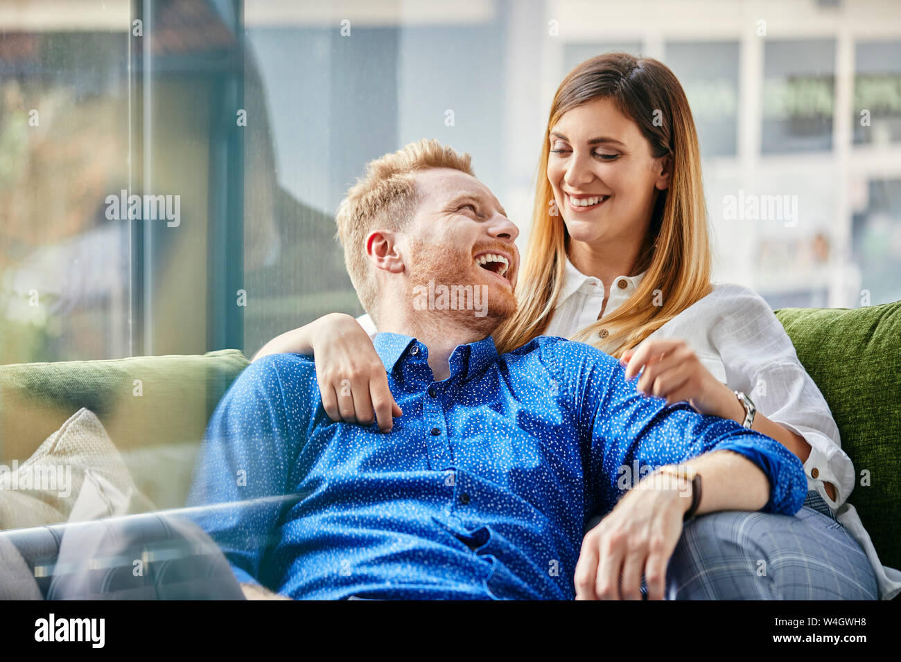 Felice coppia seduta sul lettino, con bracci intorno Foto Stock