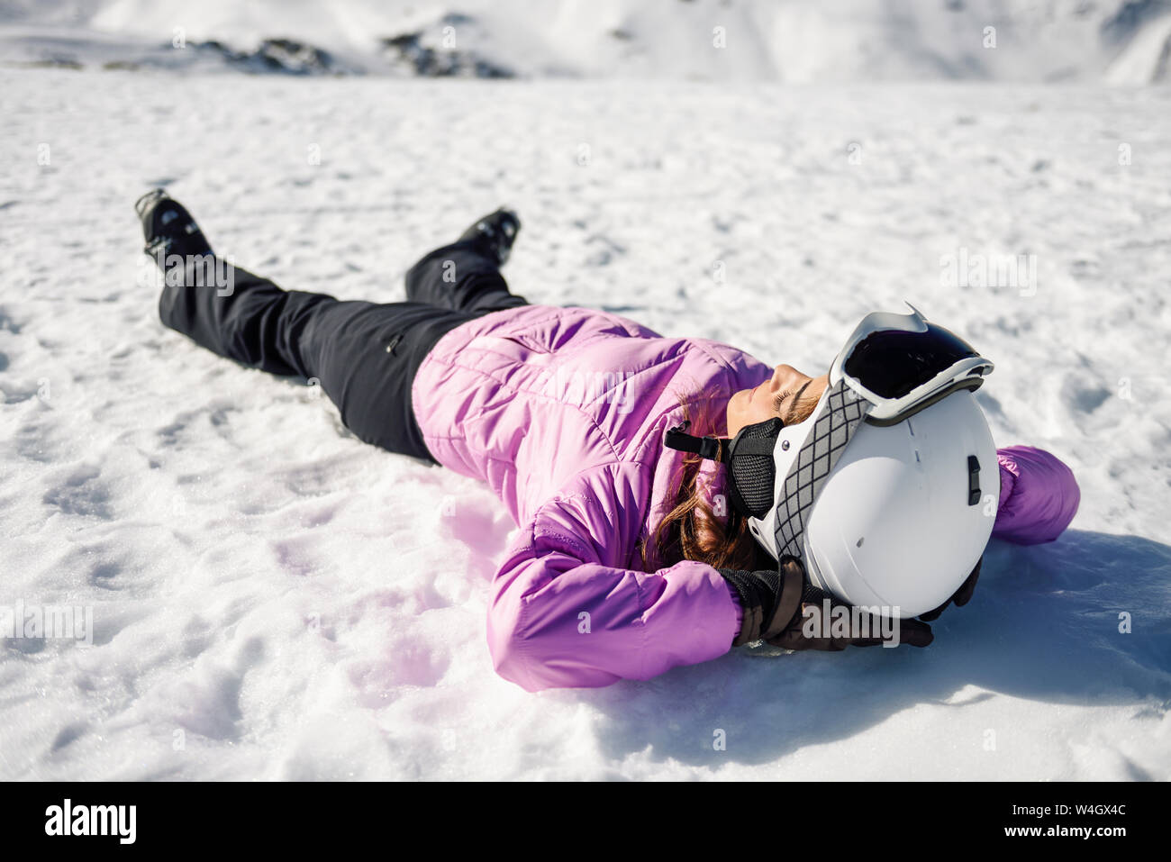 Donna prendendo una pausa dopo lo sci giacente sul terreno innevato in Sierra Nevada, Andalusia, Spagna Foto Stock
