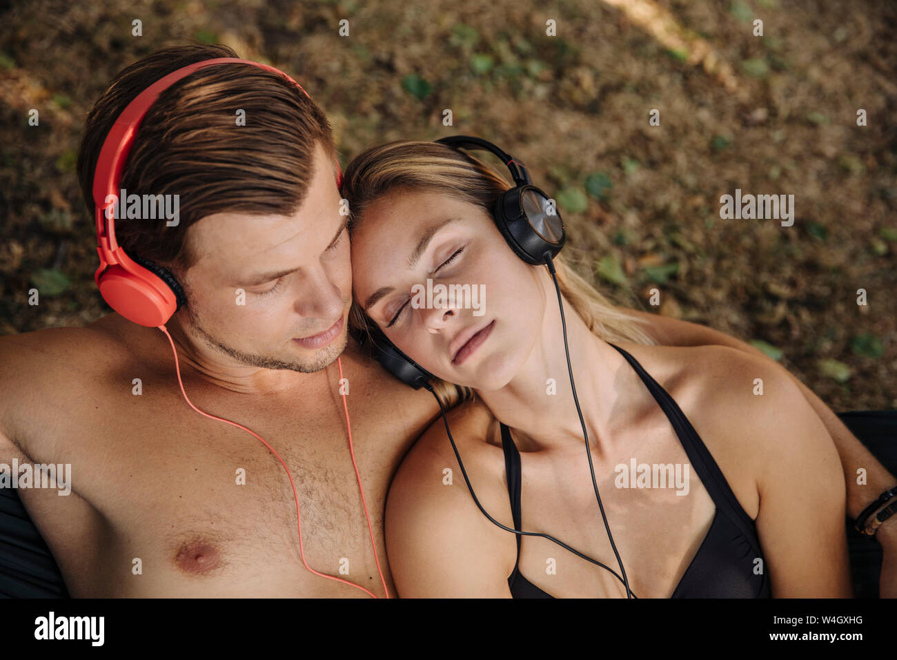 Coppia giovane giacente su erba, ascolto di musica con cuffie Foto Stock