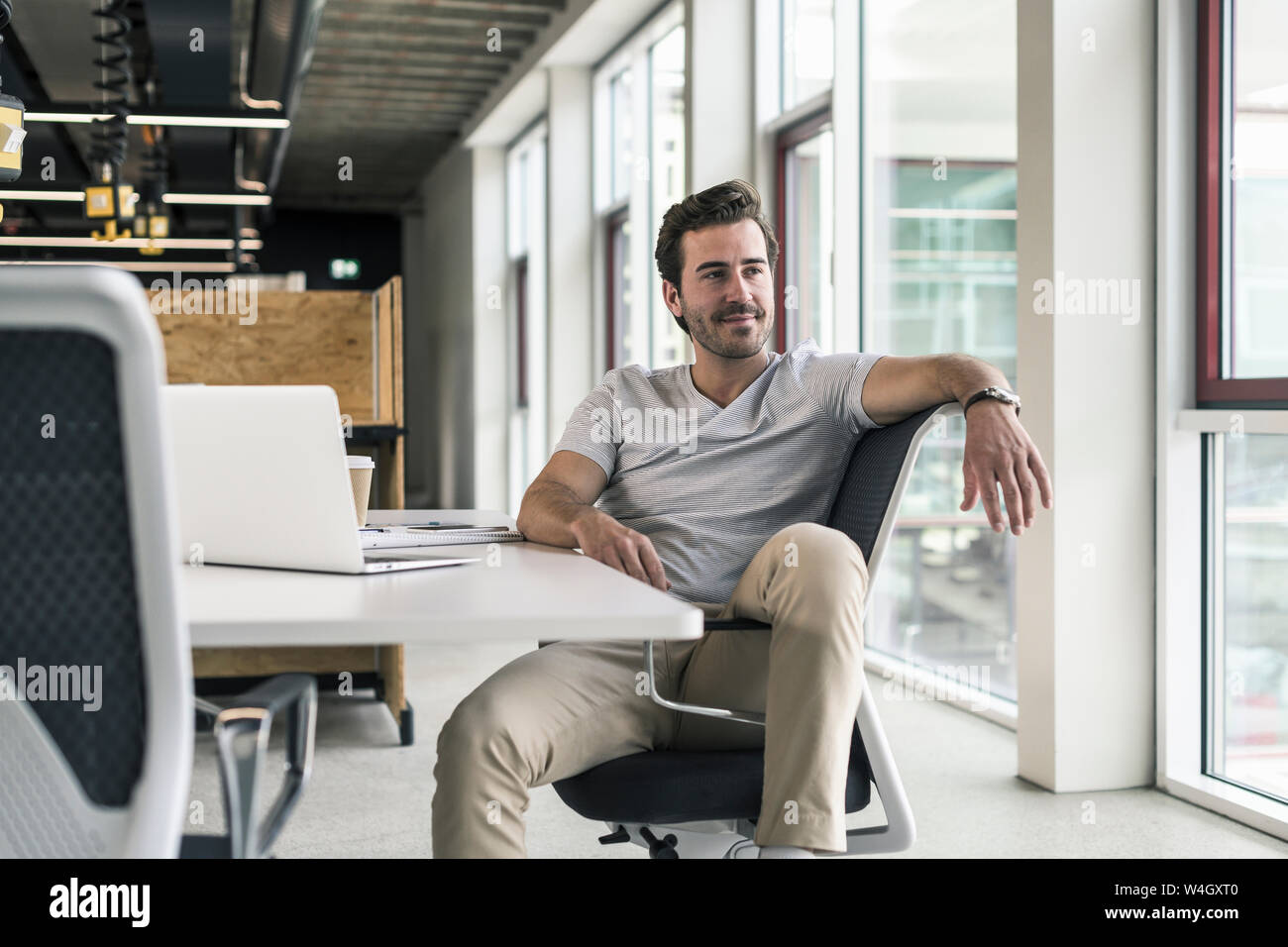 Giovane imprenditore lavora rilassato in un ufficio moderno, pensando Foto Stock