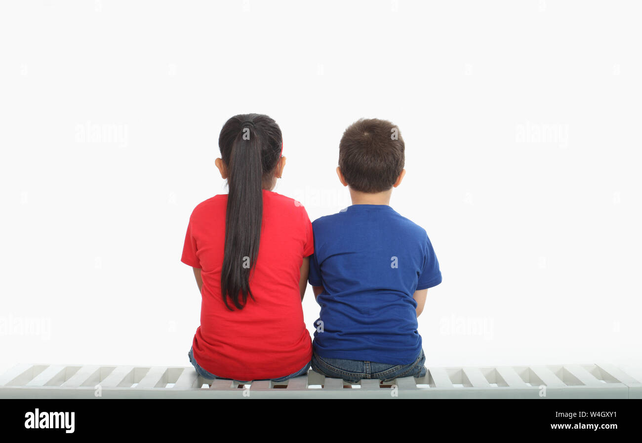 Vista posteriore di due indiani bambini seduti su un banco di lavoro Foto Stock