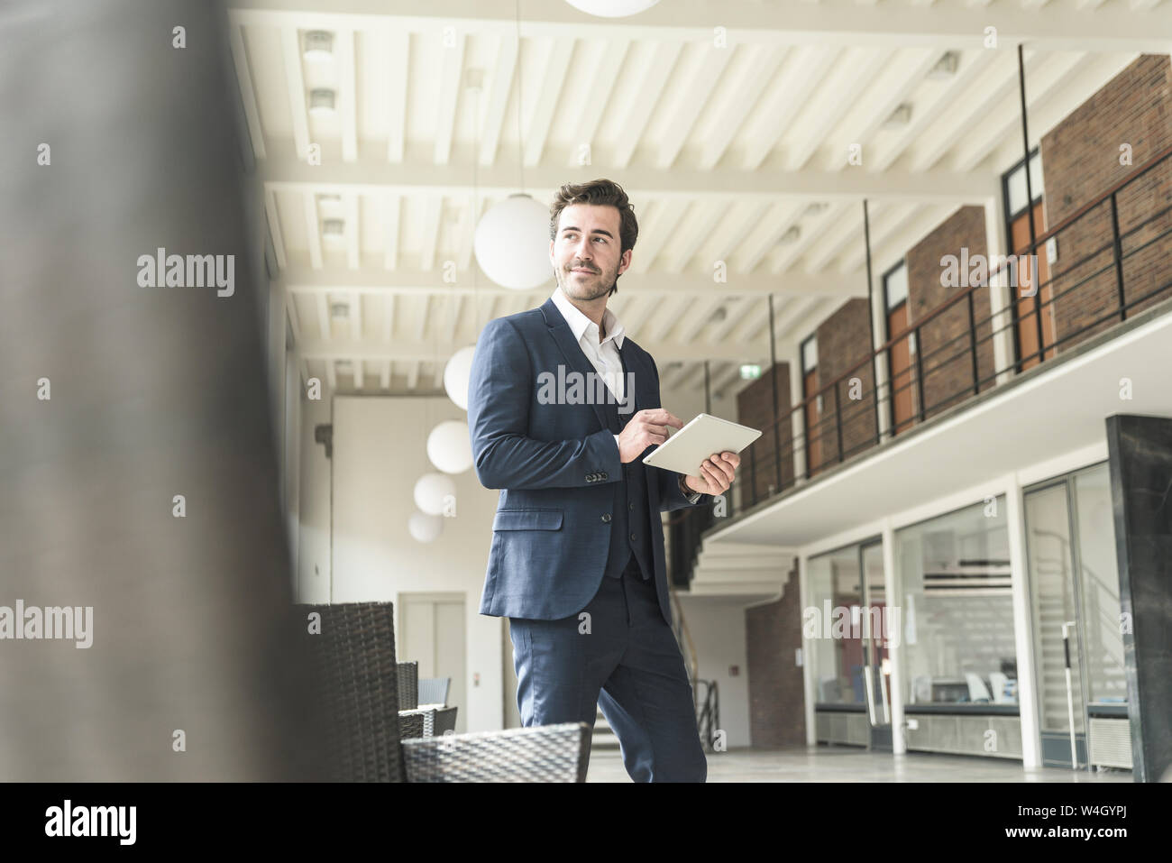 Manager di successo in piedi in un ufficio moderno edificio, utilizzando laptop Foto Stock