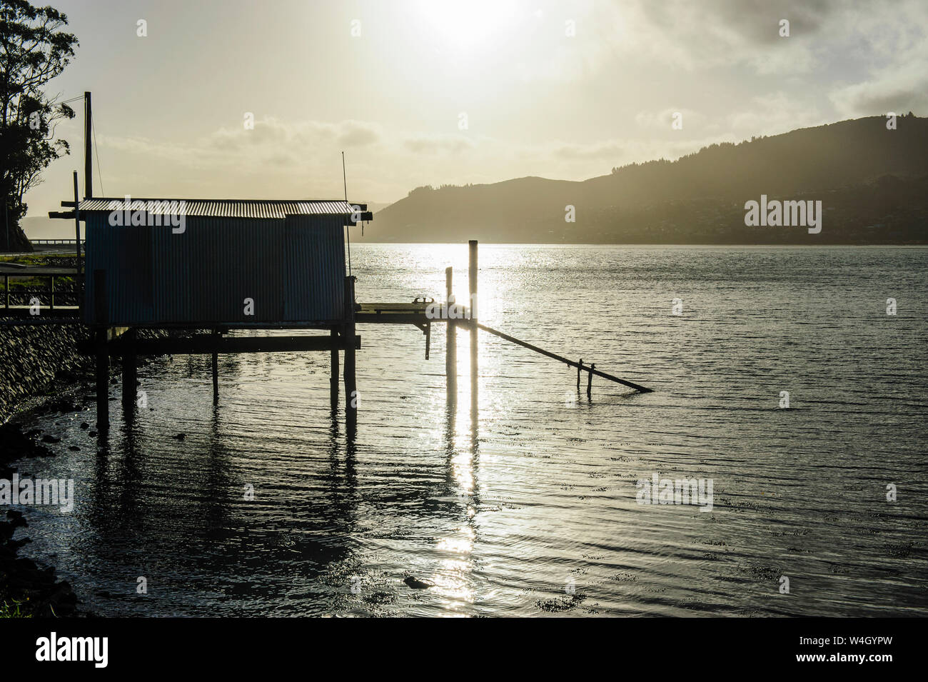 La retroilluminazione di un capanno di pesca sulla penisola di Otago, Isola del Sud, Nuova Zelanda Foto Stock