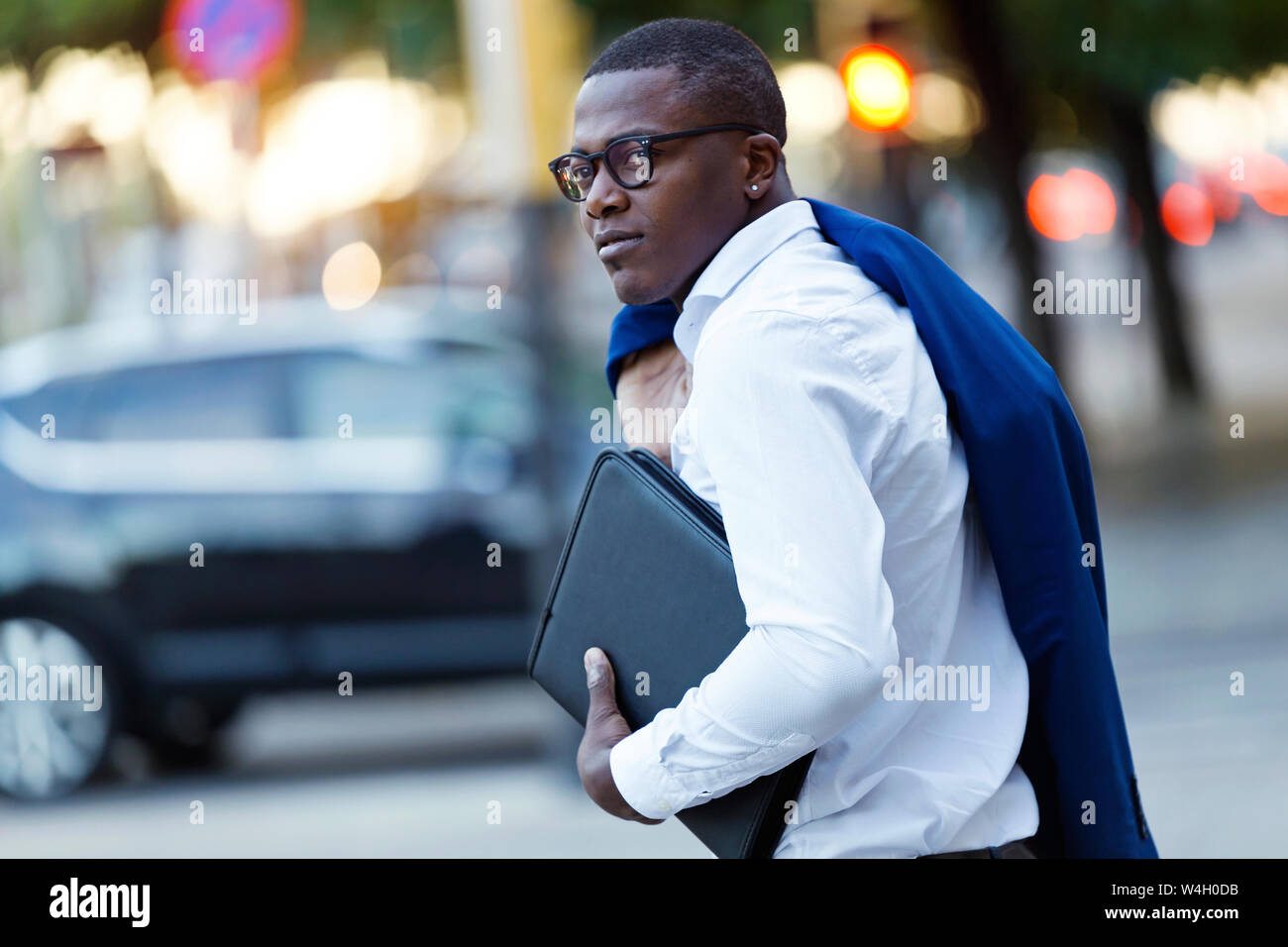 Giovane imprenditore con tuta blu camicia al di sopra la sua spalla e la borsa per notebook Foto Stock