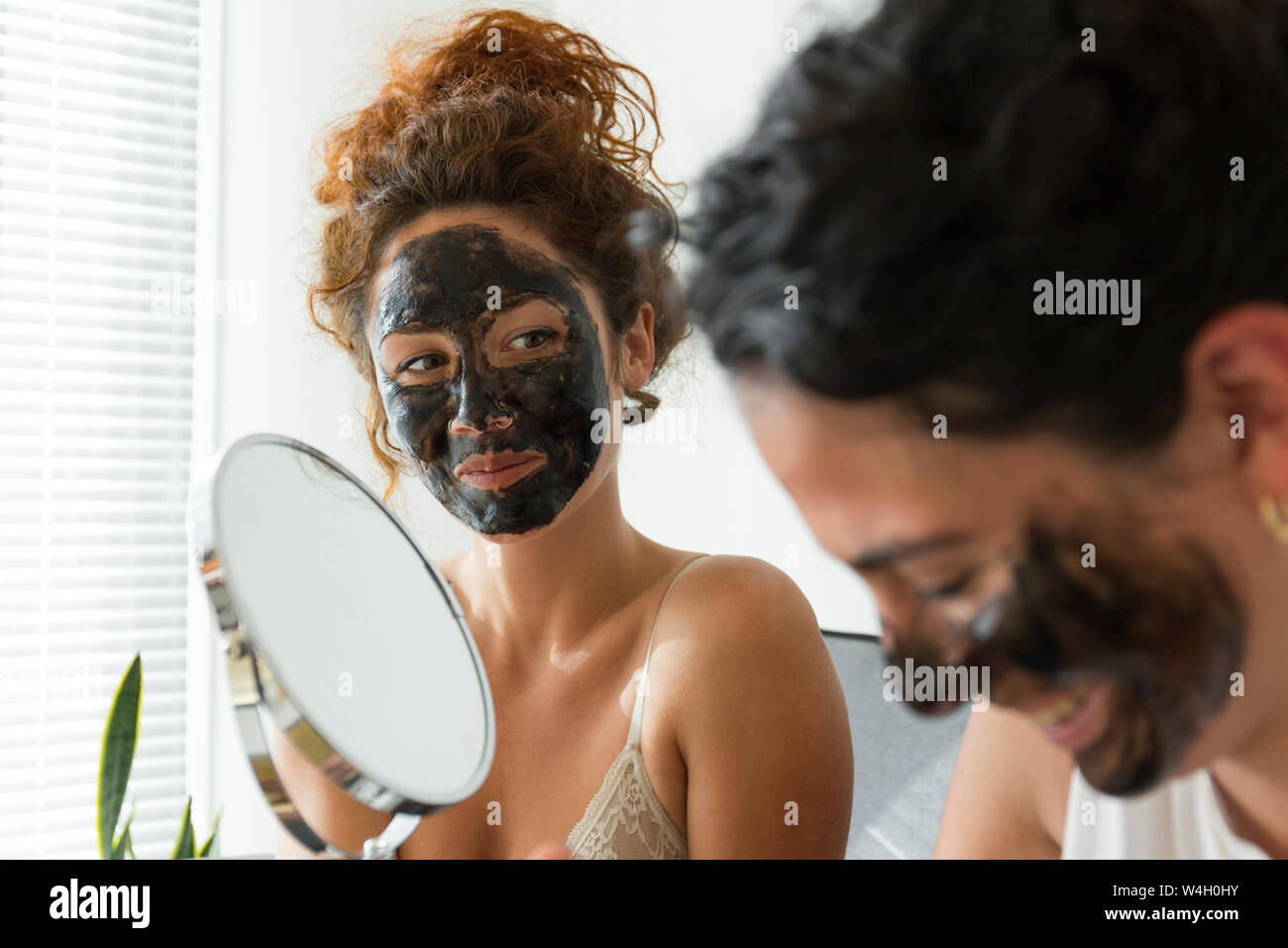 Felice di due giovani donne che indossano maschere per il viso a casa Foto Stock