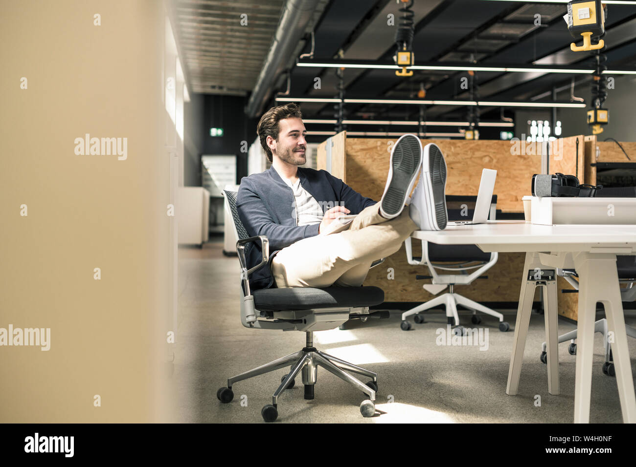 Giovane imprenditore lavora rilassato in un ufficio moderno, prendendo appunti Foto Stock