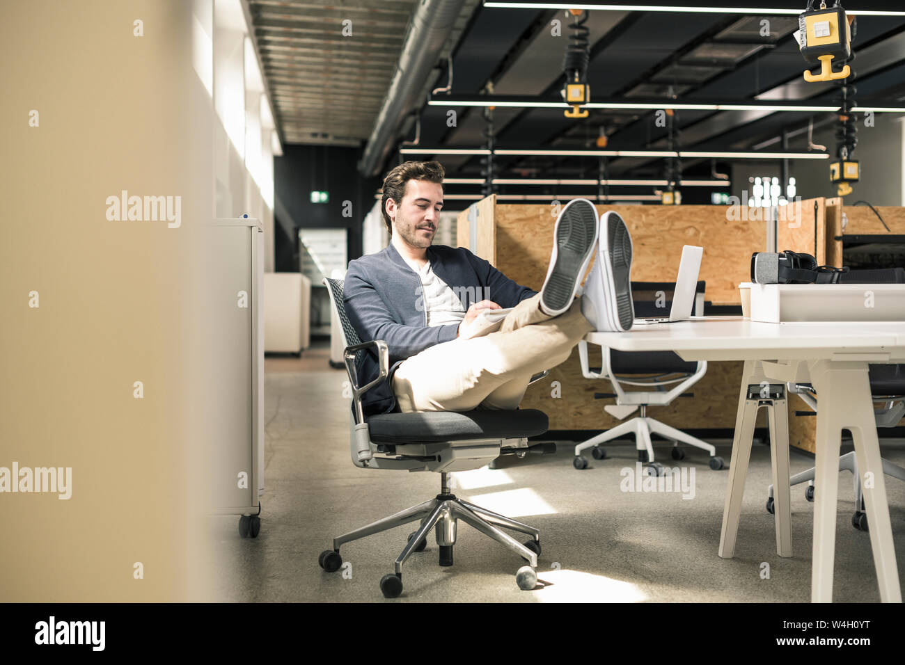 Giovane imprenditore lavora rilassato in un ufficio moderno, prendendo appunti Foto Stock