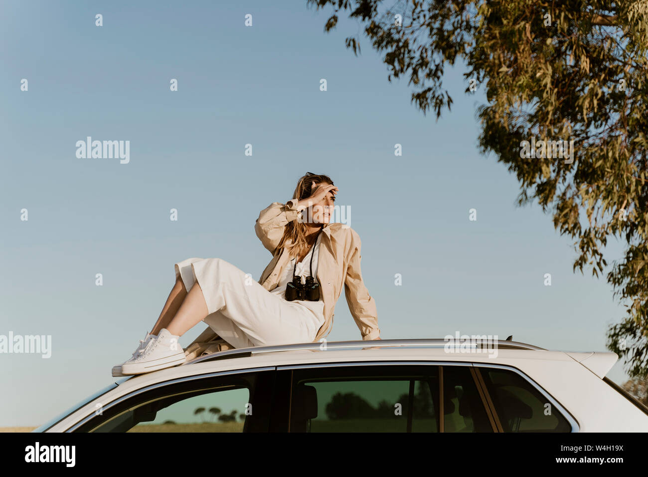 Viaggiatore femmina seduto sul bianco tetto auto Foto Stock