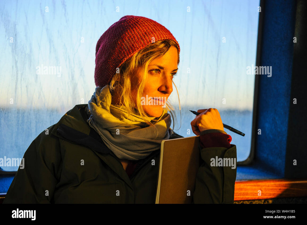 Ritratto di donna in presenza di luce solare in corrispondenza della finestra, Waiheke Island, isola del Nord, Nuova Zelanda Foto Stock