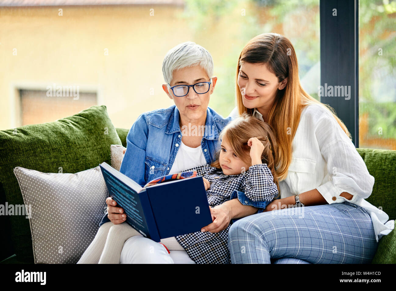 La madre e la figlia e la nipote seduta sul lettino, la lettura di un libro Foto Stock
