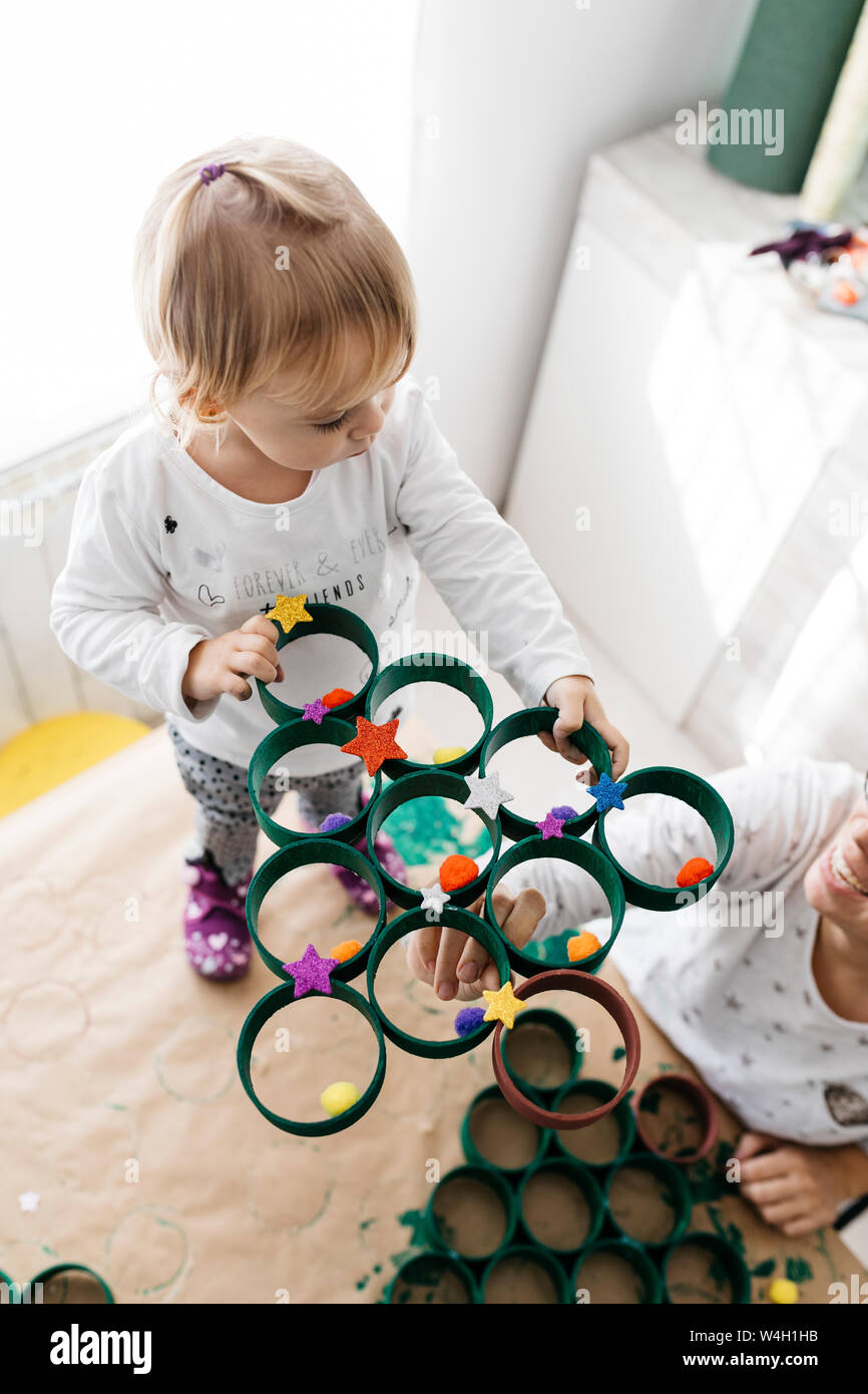 Madre e figlia fare artigianato a casa con accessori per fare un albero di Natale Foto Stock