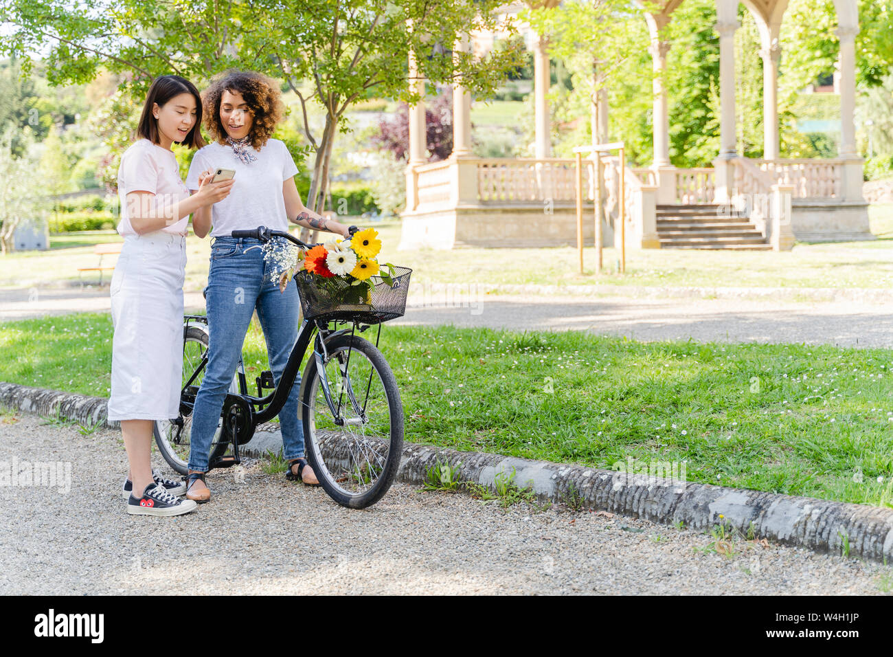Due donne con la bicicletta e il telefono cellulare in posizione di parcheggio Foto Stock