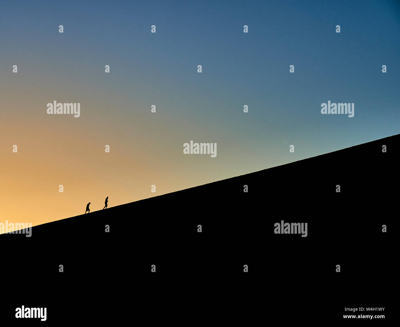 Silhouette di due persone escursionismo su Big Daddy di sunrise, Namib Desert, Namibia Foto Stock